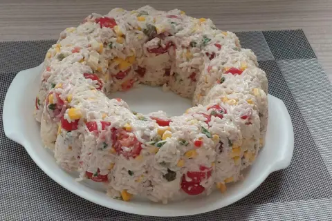 Salade de riz en forme de couronne, garnie de tomates cerises, maïs et persil.