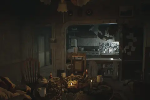 Mroczna jadalnia z obficie zastawionym stołem i śpiącym mężczyzną. W tle kuchnia, jak z poradnika Resident Evil 7.