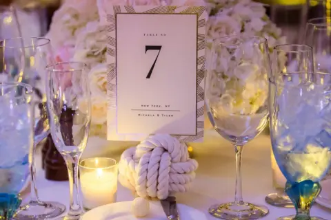 Décoration de table pour un mariage thème marin : numéro de table 7, nœud marin, bougie et verres bleus.