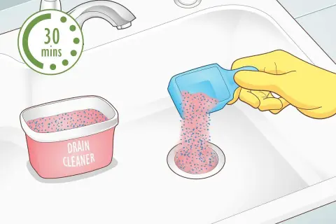 Rękawica w żółtej rękawiczce wsypuje granulat do odpływu zlewu. Obok stoi pojemnik z napisem "DRAIN CLEANER". Czas oczekiwania to 30 minut.