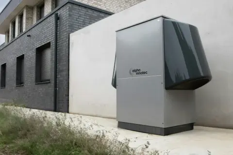 Une pompe à chaleur Alpha Innotec est installée près d'un bâtiment moderne. Elle fonctionne pour réguler la température, mais combien de temps tourne une pompe à chaleur par jour ?