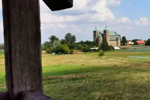 Wnętrze kolegiaty z rzędami drewnianych ławek i witrażami w oknach.