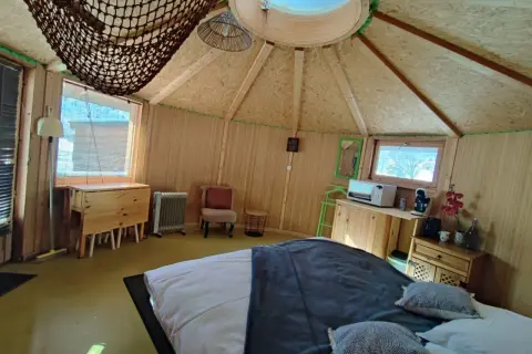 Intérieur douillet d'une yourte au col du Festre, avec un lit confortable, une kitchenette et une vue sur la nature.
