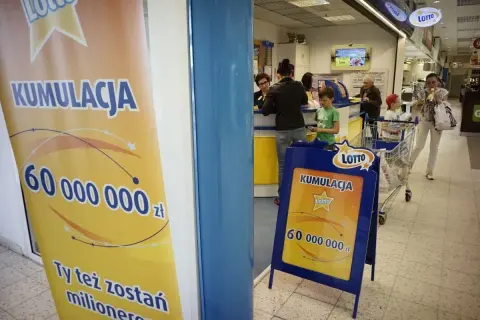 Baner i stojak reklamowy Lotto z informacją o kumulacji 60 milionów złotych.