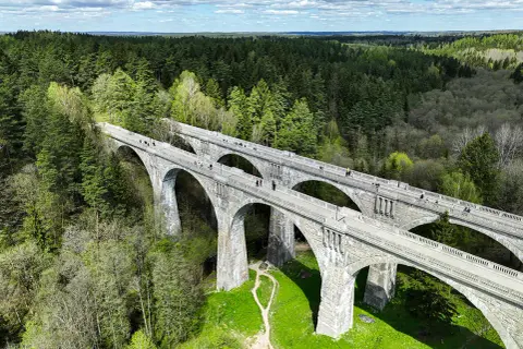 Kamienne wiadukty, dawna ścieżka rowerowa trasą kolejki wąskotorowej, otoczone bujnym lasem.