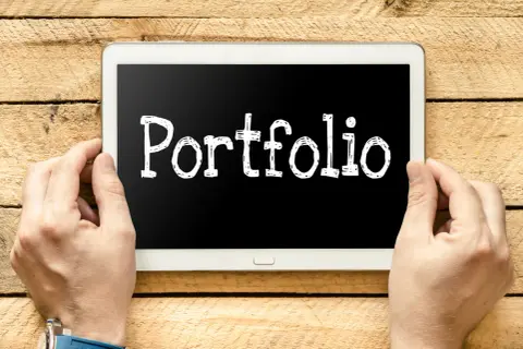Ręce trzymają tablet z napisem "Portfolio". Szukasz e-portfolio przykłady?