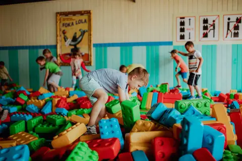 Dzieci budują wesołe konstrukcje z wielkich klocków w kolorowym parku rozrywki dla małych dzieci.