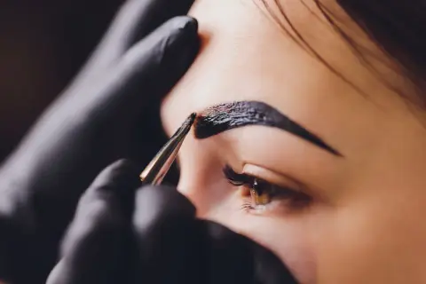 Stylist nakłada hennę na brwi. Zastanawiasz się, ile kosztuje henna?