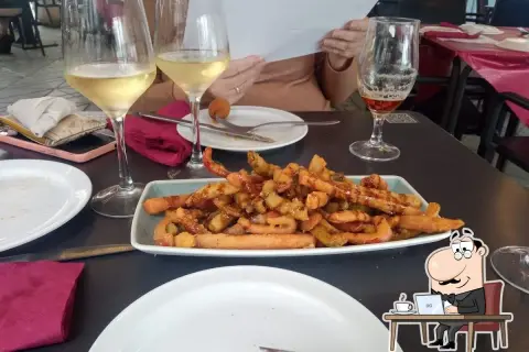 Tapas y copas de vino en el bar La Cala Almería. Un plato de patatas fritas con salchichas y una cerveza acompañan la comida.