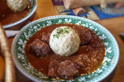 Herzhaftes Gulasch mit Klößen, ein klassisches Gulasch Rezept, serviert auf einem Teller mit grünem Muster.