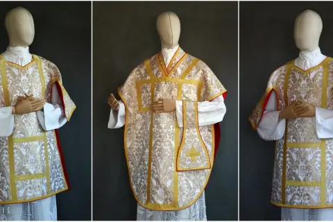 Elegancka wierzchnia szata liturgiczna z białego jedwabiu ze złotym haftem i czerwonym podszyciem.