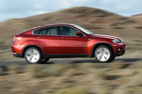 Czerwony BMW X6 pędzi po pustynnej drodze. Oto moto!