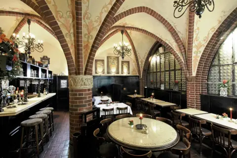 Gemütliche Atmosphäre in einem Berliner Restaurant mit Gewölbedecke, Kronleuchtern und Holztischen.