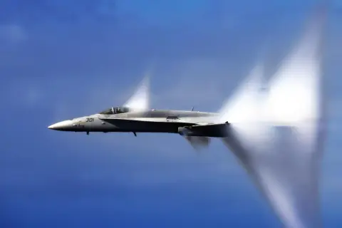 Myśliwiec F/A-18 Super Hornet przekracza barierę dźwięku, tworząc stożki kondensacji. Niesamowita prędkość samolotu w akcji.