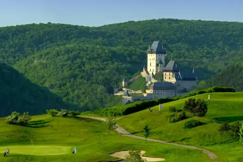 Burg Karlštejn thront majestätisch über einer grünen Golflandschaft.