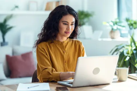 Femme concentrée sur son ordinateur portable, effectuant une recherche sur la naissance d'une personne.