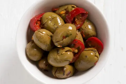 Olive verdi schiacciate con peperoncino rosso in una ciotola bianca. Perfette per un antipasto veloce, ecco come fare le olive verdi schiacciate.