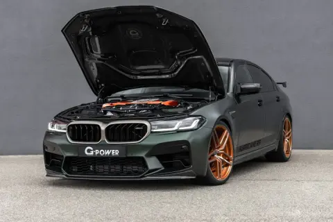 Mocarny BMW M5 G Power z otwartą maską, prezentujący pomarańczowy silnik i miedziane felgi.