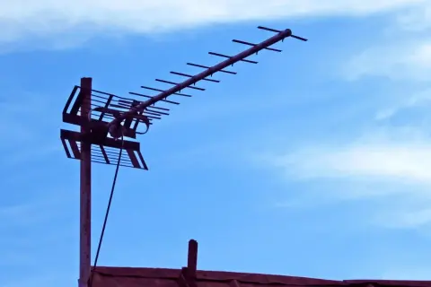 Antena naziemna do odbioru sygnału DVB-T na tle błękitnego nieba z chmurami.