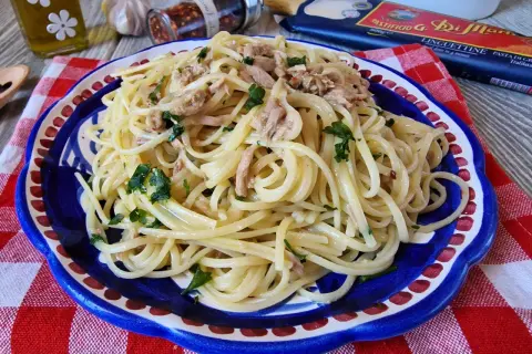 Un piatto di linguine con tonno e prezzemolo, condito con olio e peperoncino. Un classico della pasta al tonno in bianco, pronto per essere gustato.