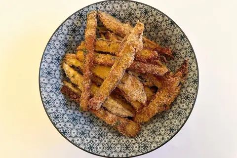 Bastoncini di melanzane impanate, un classico delle ricette della nonna, serviti in una ciotola decorata.