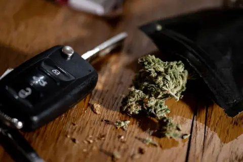 Autoschlüssel und Cannabis auf Holztisch. Ein gefährlicher Gedanke: Cannabis am Steuer.