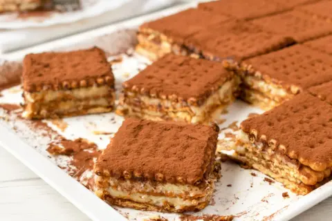 Pyszne, tanie ciasto bez pieczenia z herbatnikami, posypane kakao. Idealne na deser.
