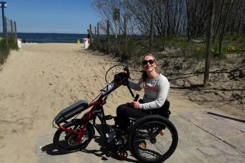Kobieta na wózku inwalidzkim z napędem elektrycznym na plaży.