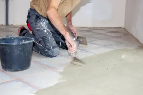 Un albañil aplica cemento para evitar que se levanten las baldosas del suelo.