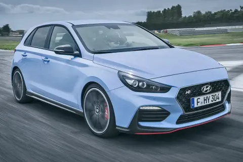 Un Hyundai i30 N azul compite en una pista, mostrando su potente motor y diseño deportivo.