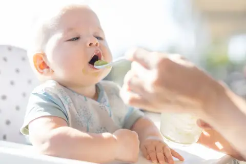 Niemowlę karmione mlekiem modyfikowanym otwiera buzię na łyżeczkę z zielonym puree. Czas zacząć rozszerzać dietę!