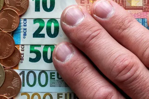 Dłonie na banknotach 10, 20, 50, 100 euro i monetach. To archiwum kursu euro.