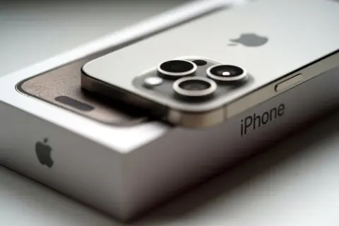 Srebrny iPhone 15 na pudełku Apple. Zbliżenie na aparat i logo. Idealne iphone 15 wymiary.