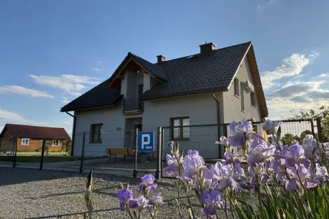 Piękne irysy kwitną przed domem w Ochabach Wielkich. W tle widać drugi budynek i parking.