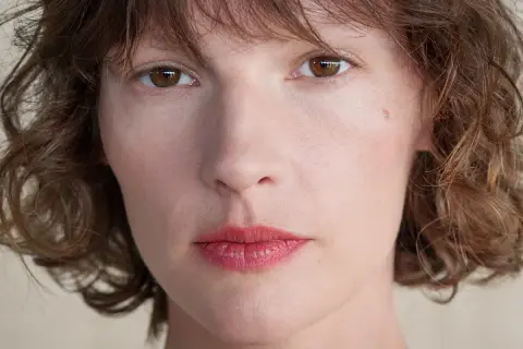 Zbliżenie na twarz kobiety z brązowymi oczami i falowanymi włosami. Retinol dla kogo? Dla każdej kobiety pragnącej odmłodzonej skóry.