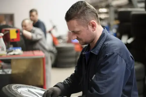 Mechanik w warsztacie naprawia oponę samochodową.