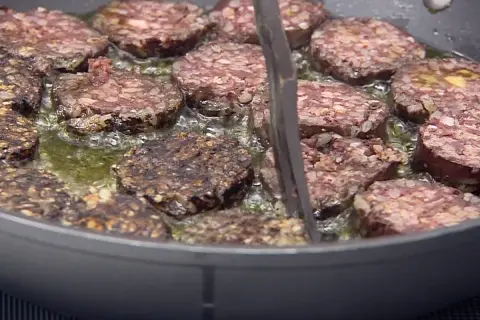 Rodajas de morcilla de Burgos dorándose en sartén con aceite burbujeante. Perfectas para tus recetas.