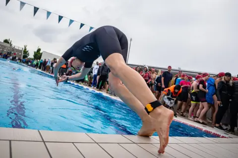 A swimmer poised to dive, embodying the motivation for swimmers to push their limits and embrace the challenge.