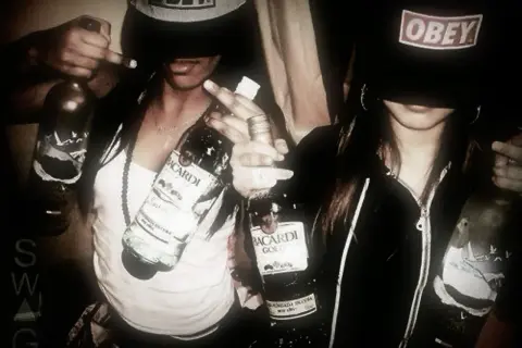 Två personer i fjortis stil med "Obey"-kepsar och Bacardi-flaskor.