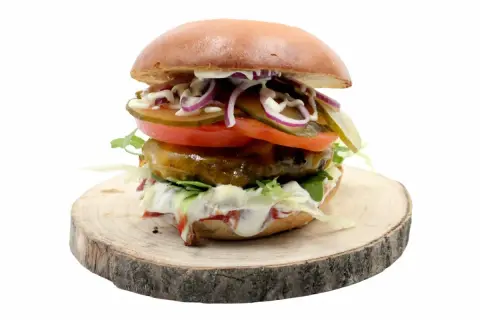 Soczysty burger z jalapeno, pomidorem, cebulą i ogórkiem na drewnianym plastrze.