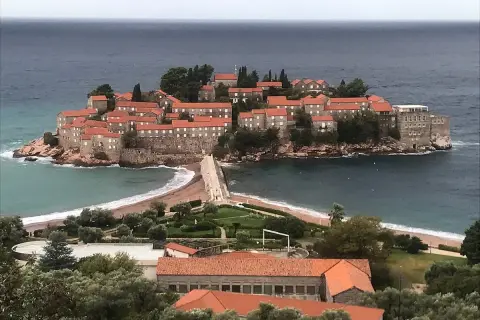 Sveti Stefan, en pittoresk ö med stenhus och röda tak, förbunden med fastlandet via en smal landremsa.