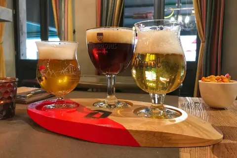 Tre bicchieri di birra su un vassoio di legno, pronti per essere gustati al tavolo.