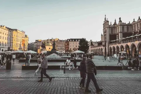 En livlig torgscen i Krakow, perfekt för din reseguide. Människor promenerar förbi historiska byggnader och marknadsstånd.