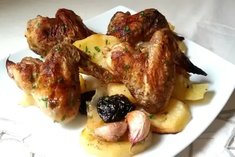 Alitas al horno con patatas, ajo y ciruelas pasas. Un plato casero y delicioso.
