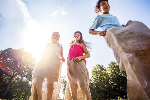 Barn hoppar säcklöpning i solen. Perfekt för tips på femkamp eller en rolig sommardag!