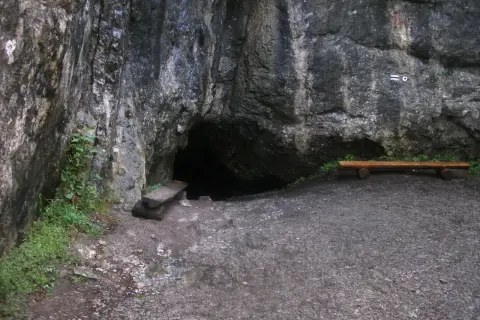 Wejście do jaskini w skale, obok ławka i kamienna ława. Tajemnicza dziura w górach, może w okolicach Zakopanego.