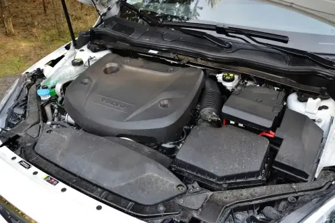Silnik D2 w Volvo V40, gotowy do pracy. Widać osłonę silnika z logo Volvo, skrzynkę bezpieczników i elementy układu dolotowego.