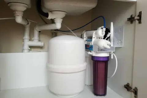 Système de filtration d'eau sous évier, incluant un réservoir blanc et un filtre violet, pour une purification par **osmose inverse**.