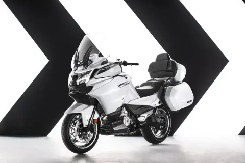 Biały, turystyczny motocykl z kuframi, jeden z nowoczesnych chińskich motocykli, prezentowany na tle czarno-białej grafiki.