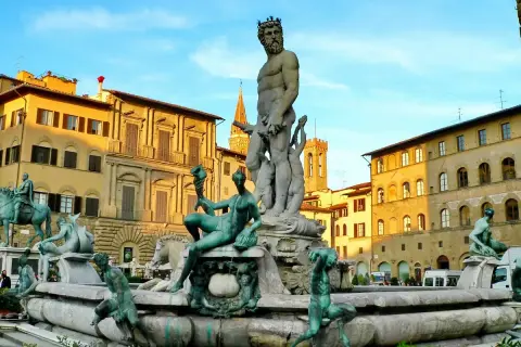 La Fontana del Nettuno a Firenze, con le sue sculture in bronzo e marmo, domina la piazza sotto un cielo azzurro.